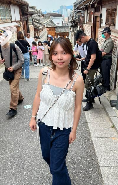 Young woman on bustling street with homes and cityscape in background